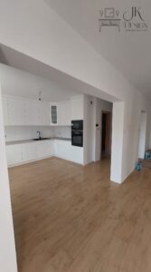 Biała kuchnia z jasno-marmurkowym blatem oraz czarnym AGD z frezowanymi uchwytami we frontach.