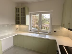 Piękne kuchnia w połączeniu kolorów bieli, trawy cytrynowej, akcentowana pozłacanymi okuciami oraz czernią