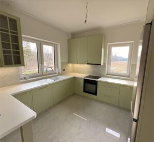 Piękne kuchnia w połączeniu kolorów bieli, trawy cytrynowej, akcentowana pozłacanymi okuciami oraz czernią